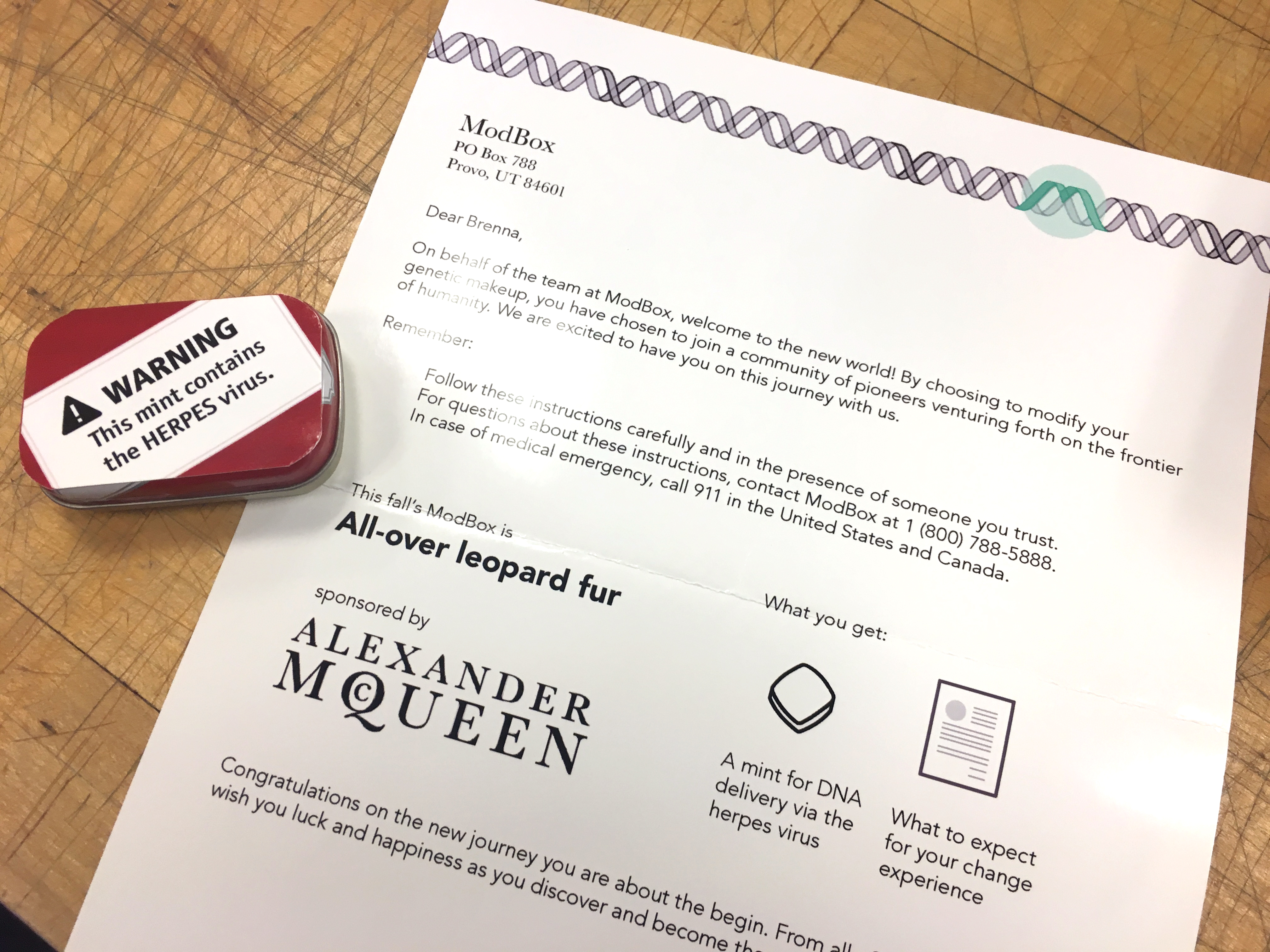 A letter welcomes another customer to the frontier of humanity with supplies to genetically modify a human with all-over leopard fur. It's sponsored by Alexander McQueen. There is a mint tin that contains the herpes virus, how the genetic modifcation is delivered.